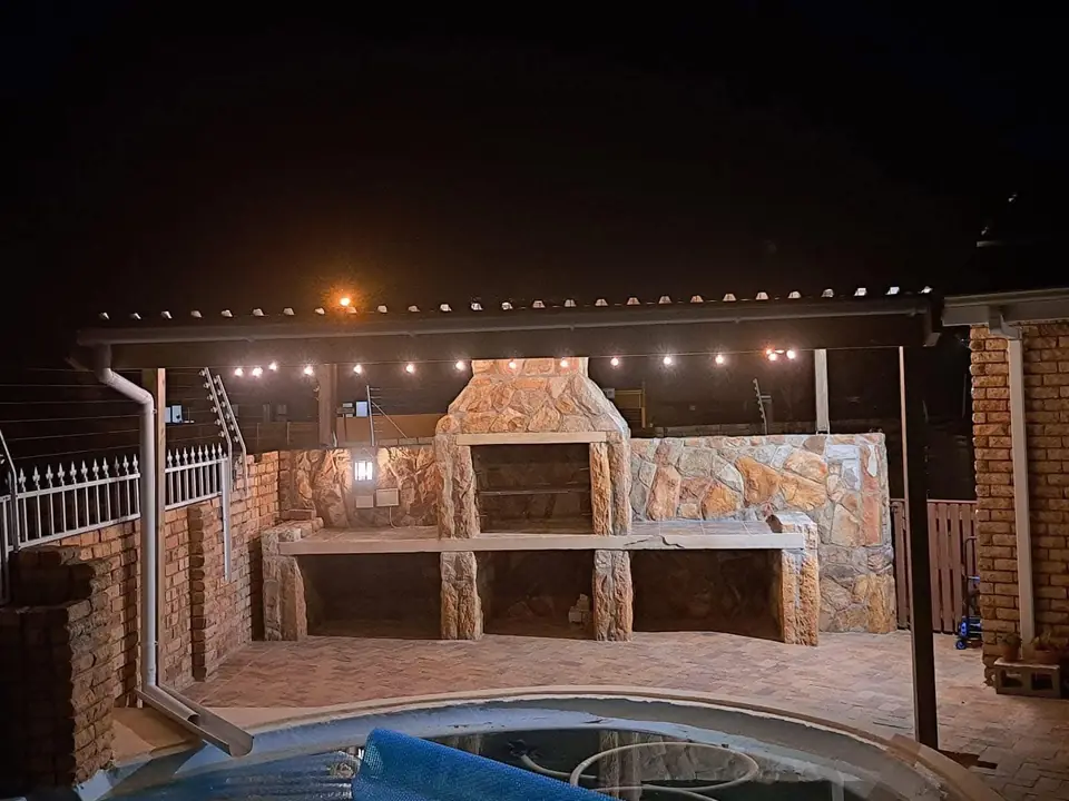 Stone braai area with string lights at night