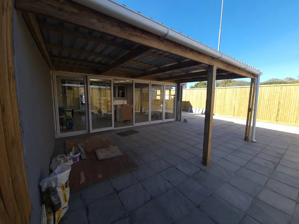 Large covered timber patio in front of glass doors