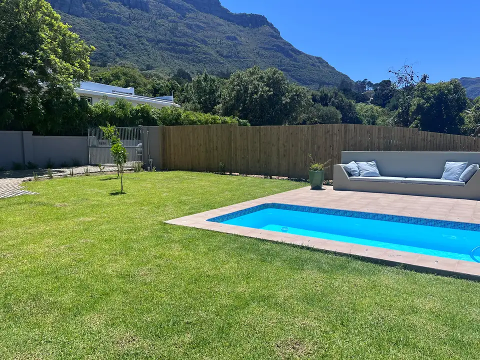 Lawn, swimming pool and timber boundary fence at a Cape Town home, with the mountain behind
