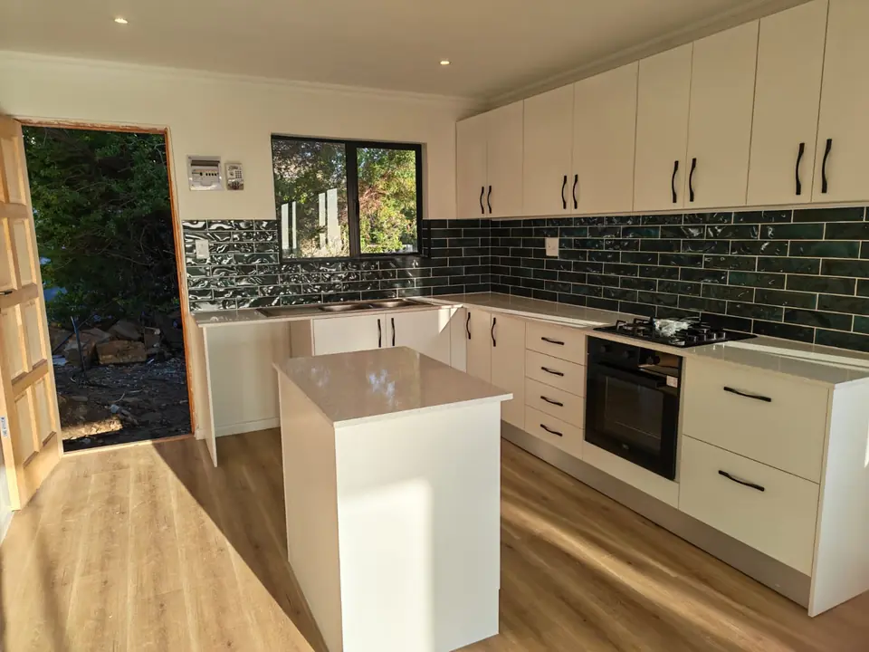 Renovated kitchen in Capri with white cabinets, stone countertops and green subway tiles