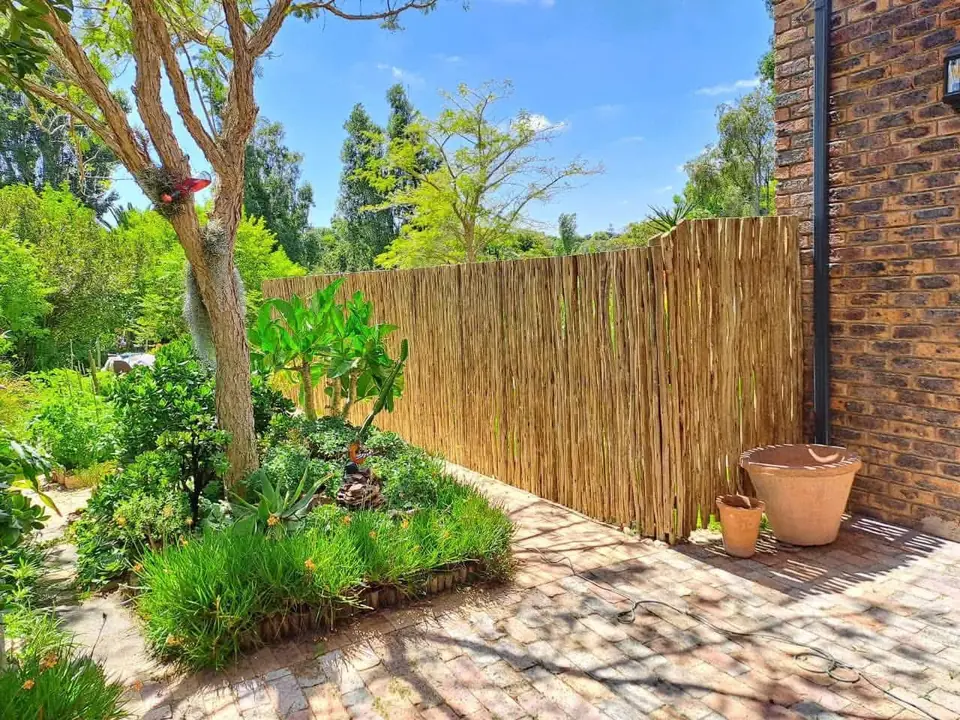 Latte (reed pole) fence along a garden path beside a brick wall