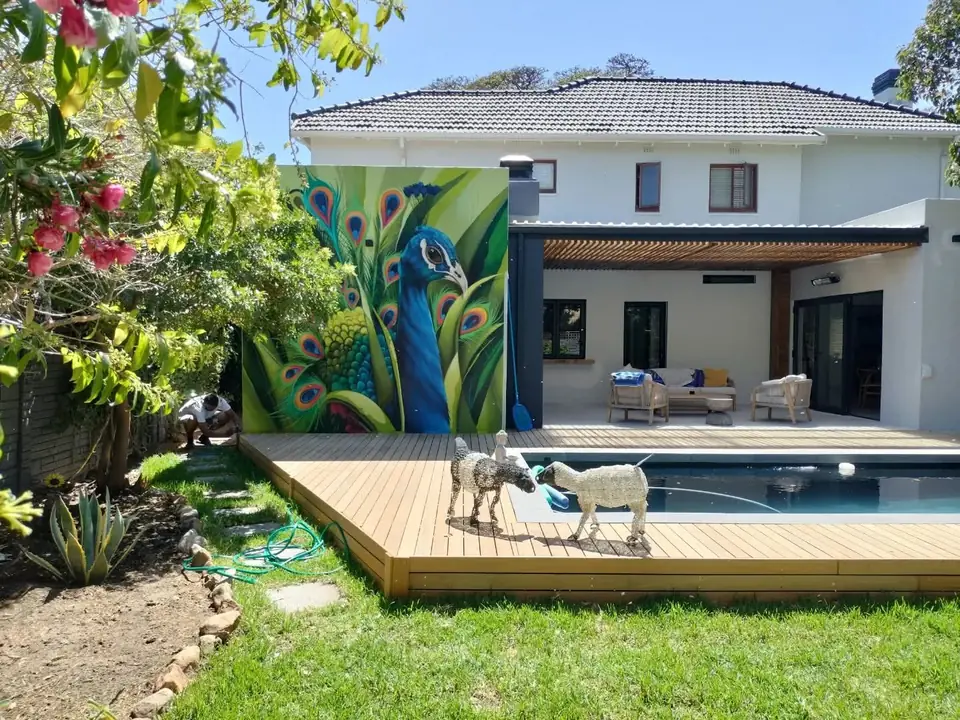 Timber pool deck and garden in front of a house with a painted mural