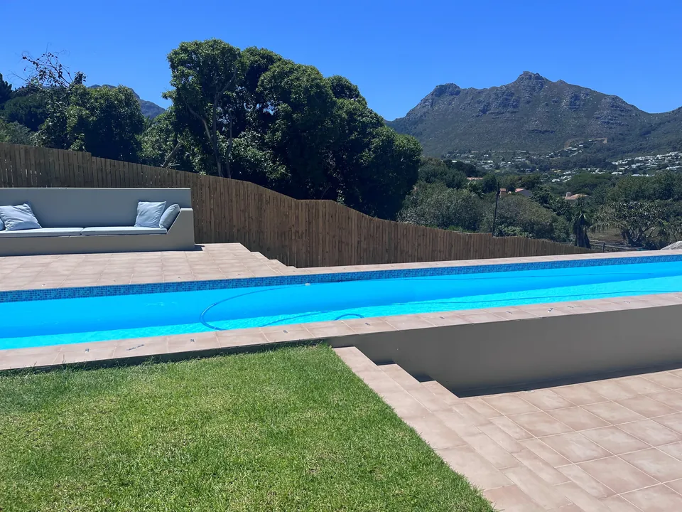 Pool, paving and lawn with a timber fence and mountain views