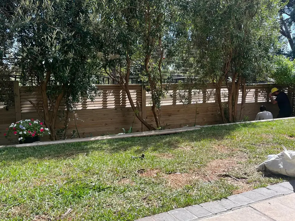 Slatted timber fence along a garden lawn