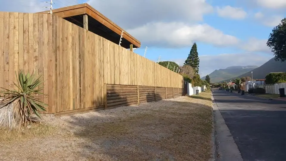 Long timber boundary fence along a street with the mountains behind