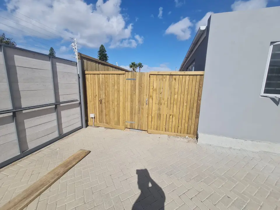 Timber gate and fence beside a paved driveway