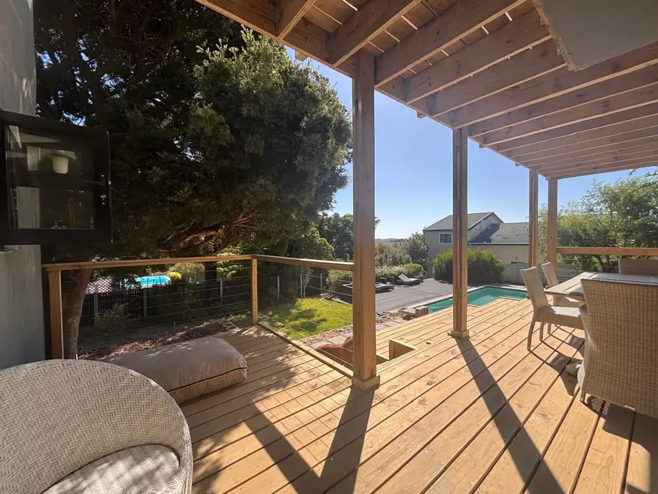 Timber pergola over a deck with a view of the pool and garden