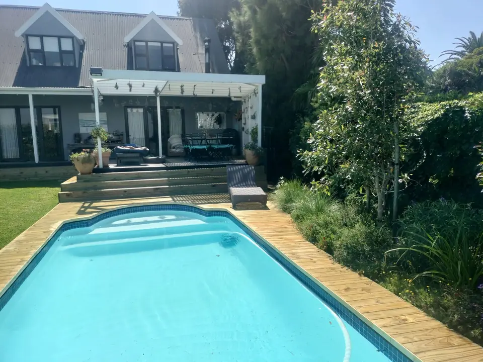 Timber deck around a swimming pool in front of a house